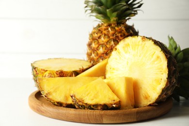 Whole and sliced fresh ripe pineapples on white table