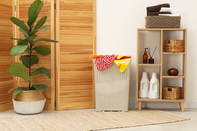 Photo of Wicker basket full of laundry in bathroom