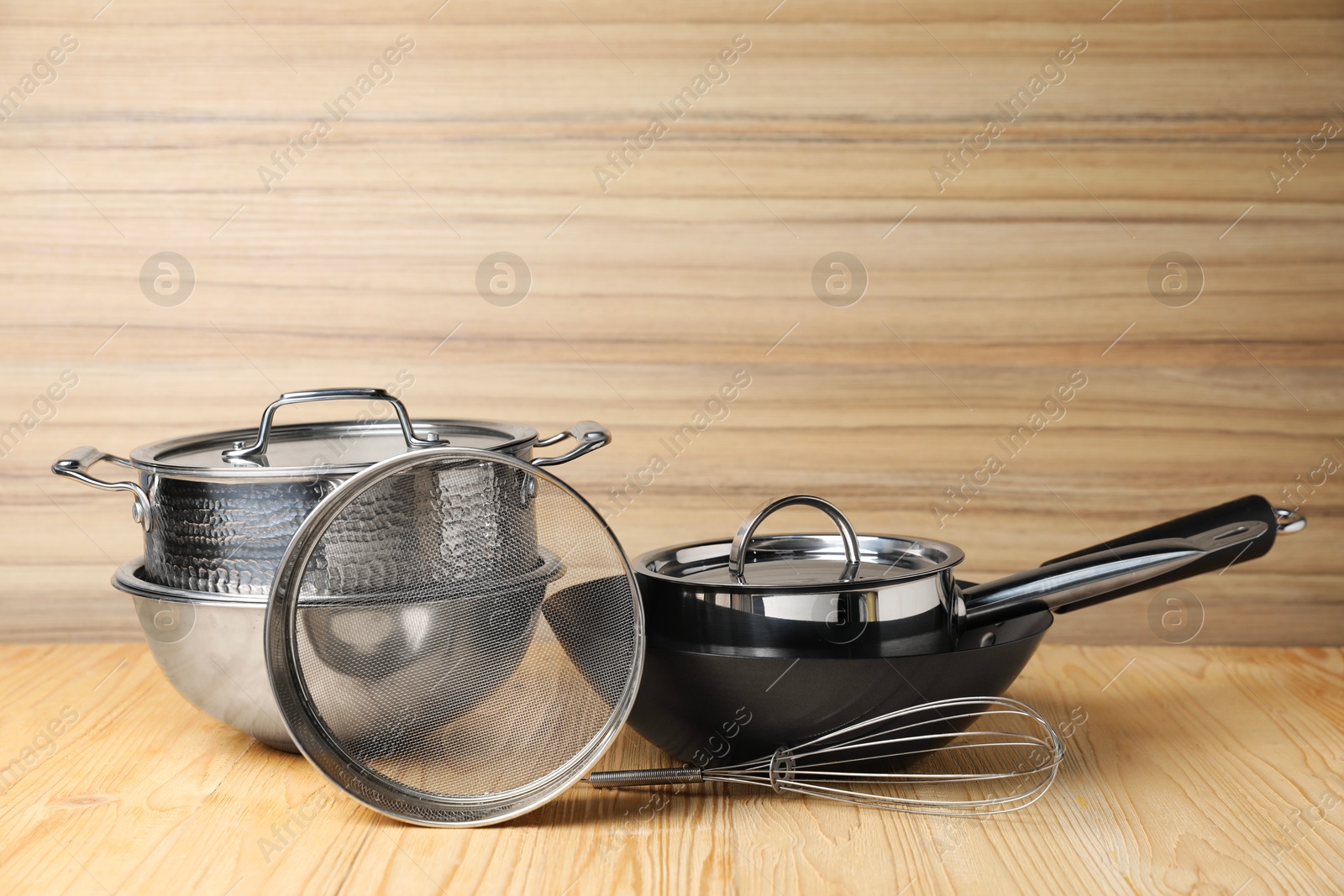 Photo of Dishware and cooking utensils on wooden table, space for text