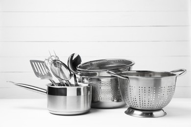 Photo of Dishware and cooking utensils on white table, space for text