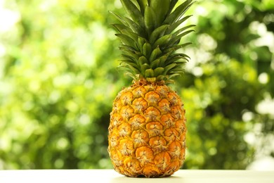 Photo of Fresh ripe pineapple on white wooden table against blurred background