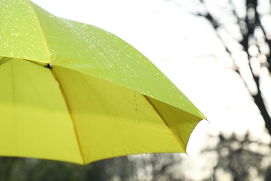 Photo of Open yellow umbrella under pouring rain outdoors, closeup. Space for text