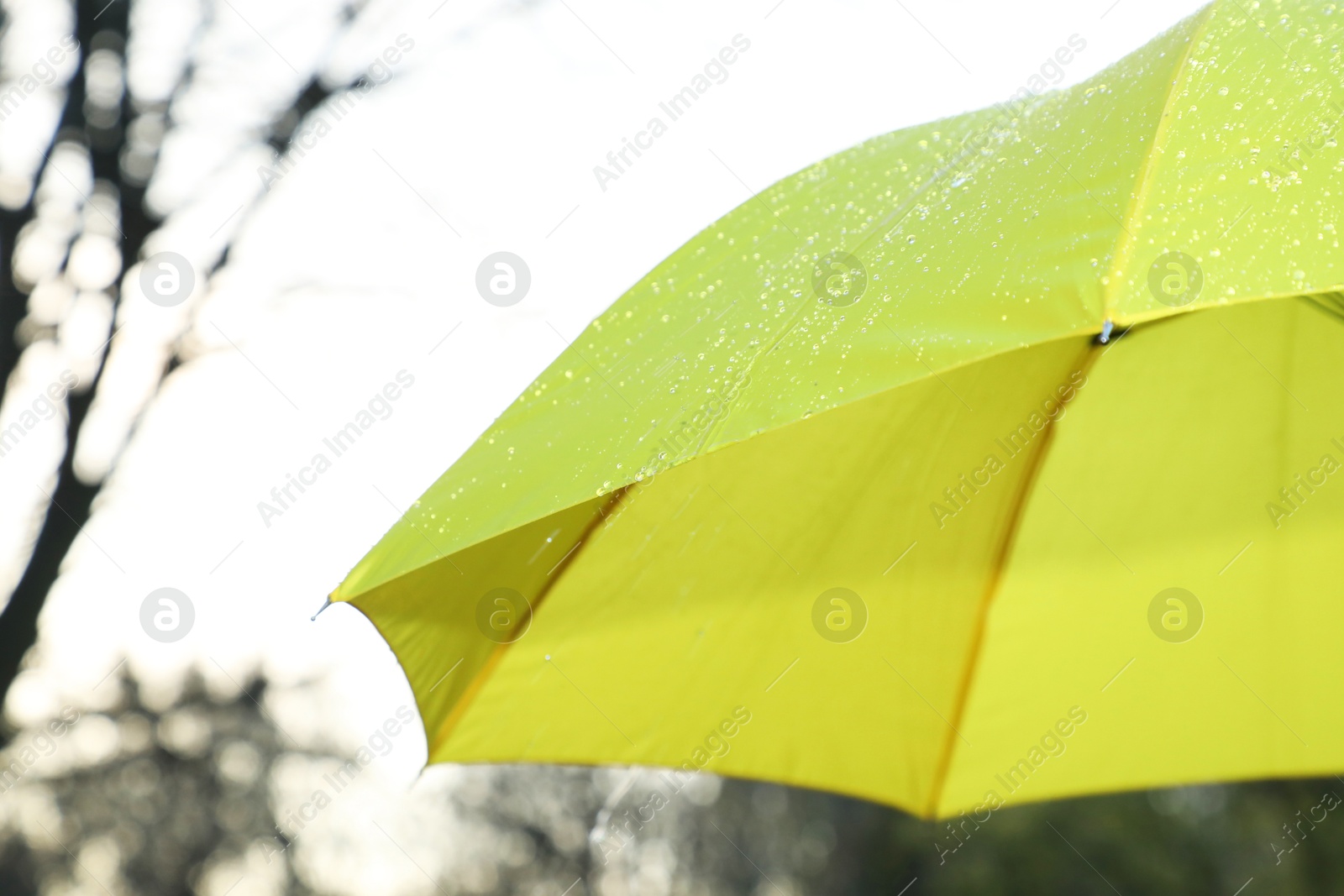 Photo of Open yellow umbrella under pouring rain outdoors, closeup. Space for text