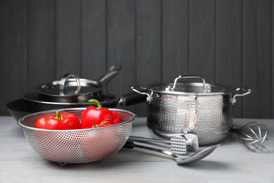 Photo of Dishware, cooking utensils and vegetables on grey wooden table