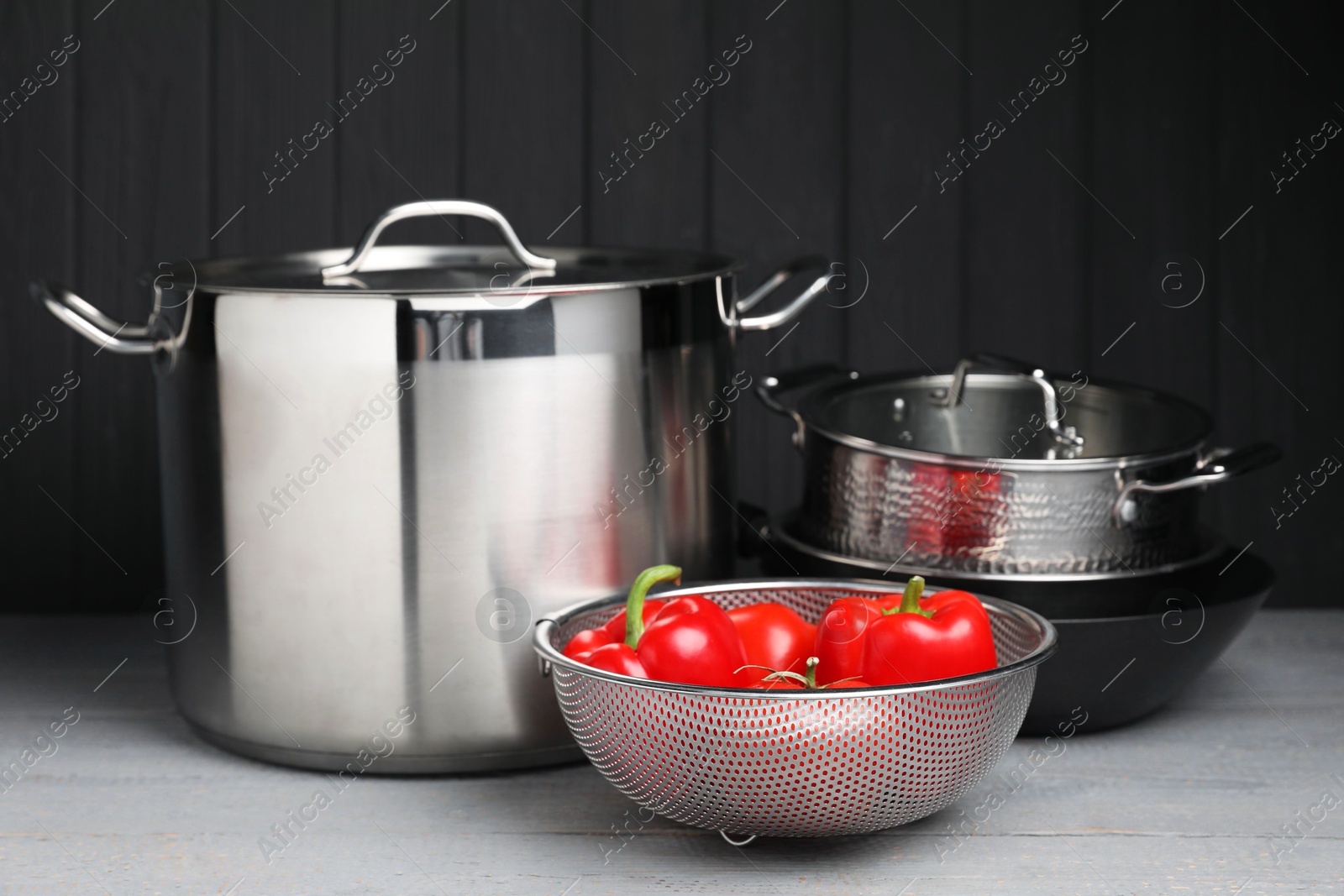 Photo of Stainless steel dishware and vegetables on grey wooden table