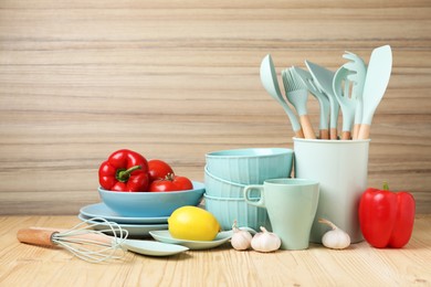 Photo of Dishware, cooking utensils, vegetables lemon and garlic on wooden table. Space for text