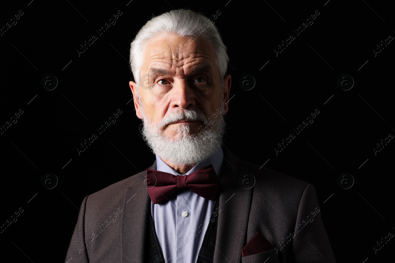 Photo of Portrait of serious senior man with silver beard on black background