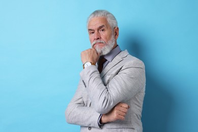 Photo of Portrait of serious senior man with silver beard on light blue background