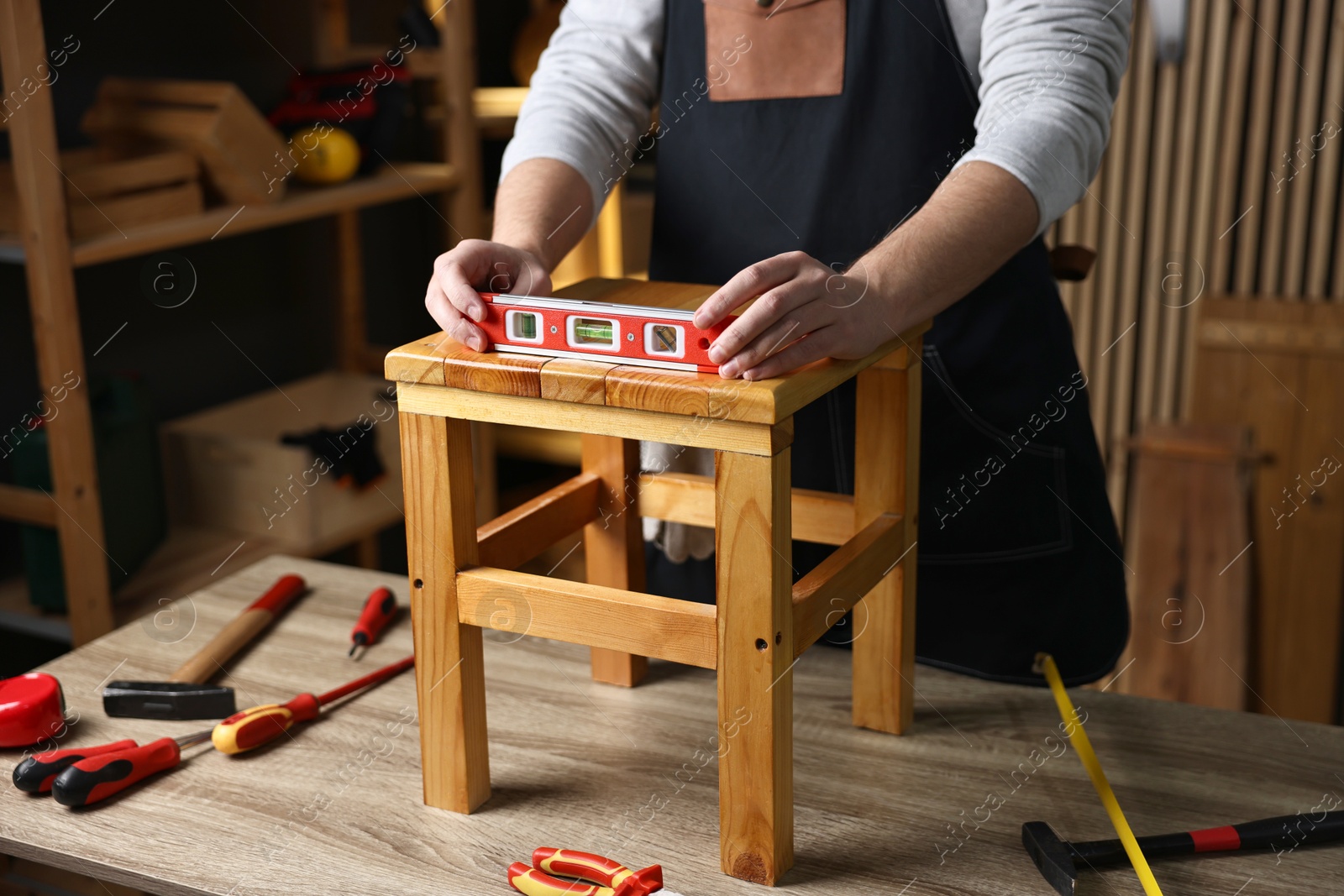 Photo of Repairman checking stool level at table in workshop, closeup