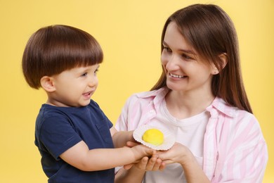 Photo of Mother and baby eating tasty mochi on yellow background