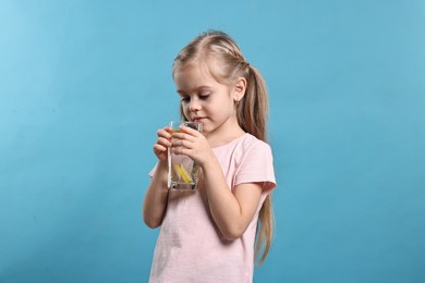 Photo of Girl with glass of lemonade on light blue background. Refreshing drink