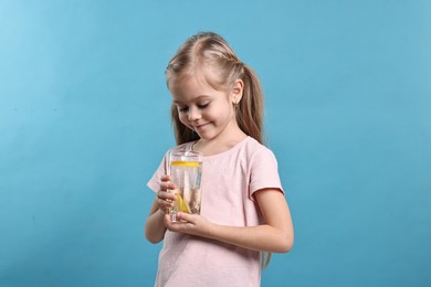 Photo of Girl with glass of lemonade on light blue background. Refreshing drink