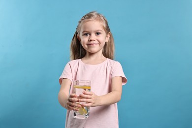 Photo of Girl with glass of lemonade on light blue background. Refreshing drink