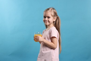 Photo of Girl with glass of orange juice on light blue background. Refreshing drink