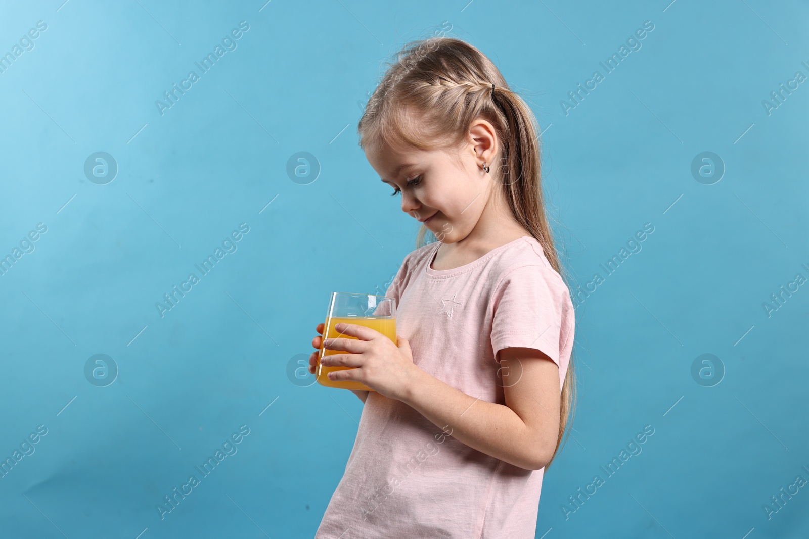 Photo of Girl with glass of orange juice on light blue background. Refreshing drink