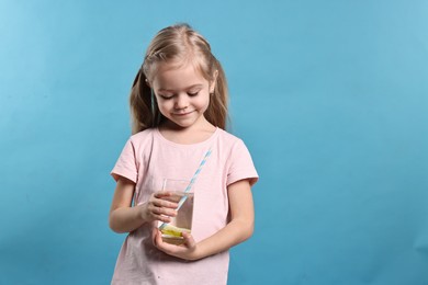 Photo of Girl with glass of lemonade on light blue background. Refreshing drink