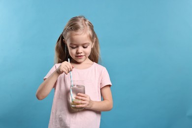 Photo of Girl with glass of lemonade on light blue background, space for text. Refreshing drink