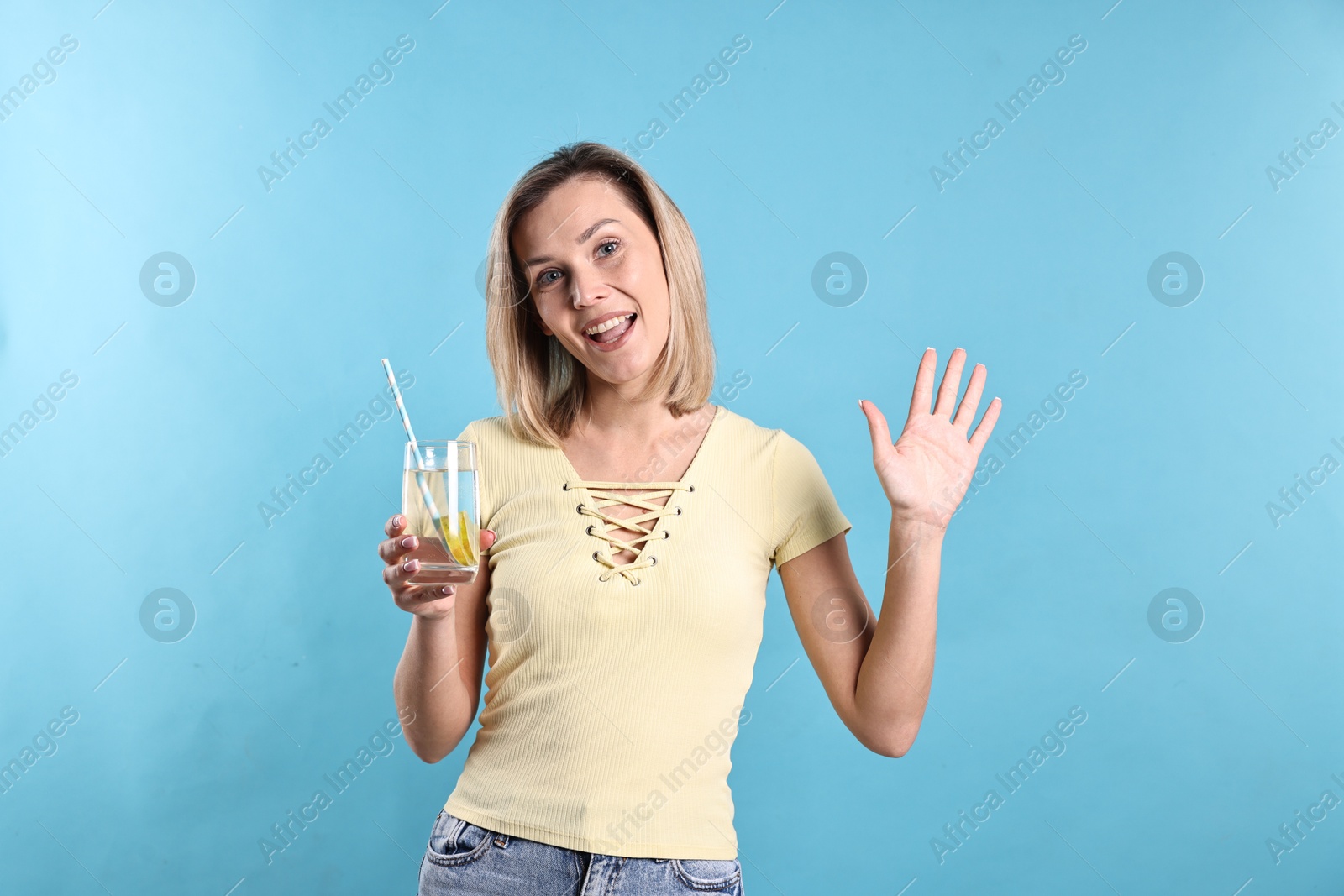 Photo of Woman with glass of lemonade on light blue background. Refreshing drink