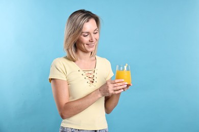 Photo of Woman with glass of orange juice on light blue background. Refreshing drink