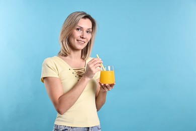 Photo of Woman with glass of orange juice on light blue background, space for text. Refreshing drink