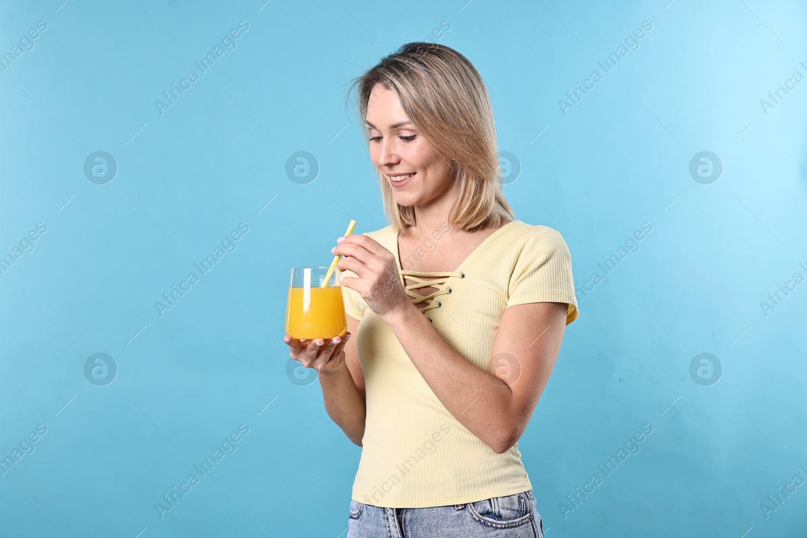 Photo of Woman with glass of orange juice on light blue background. Refreshing drink