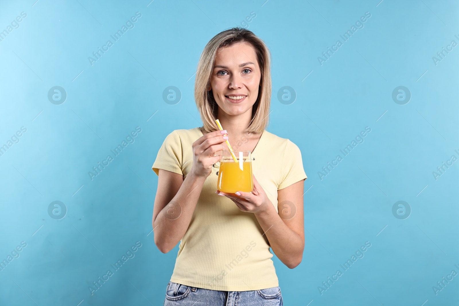 Photo of Woman with glass of orange juice on light blue background. Refreshing drink