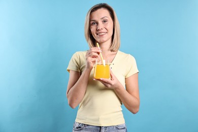 Photo of Woman with glass of orange juice on light blue background. Refreshing drink