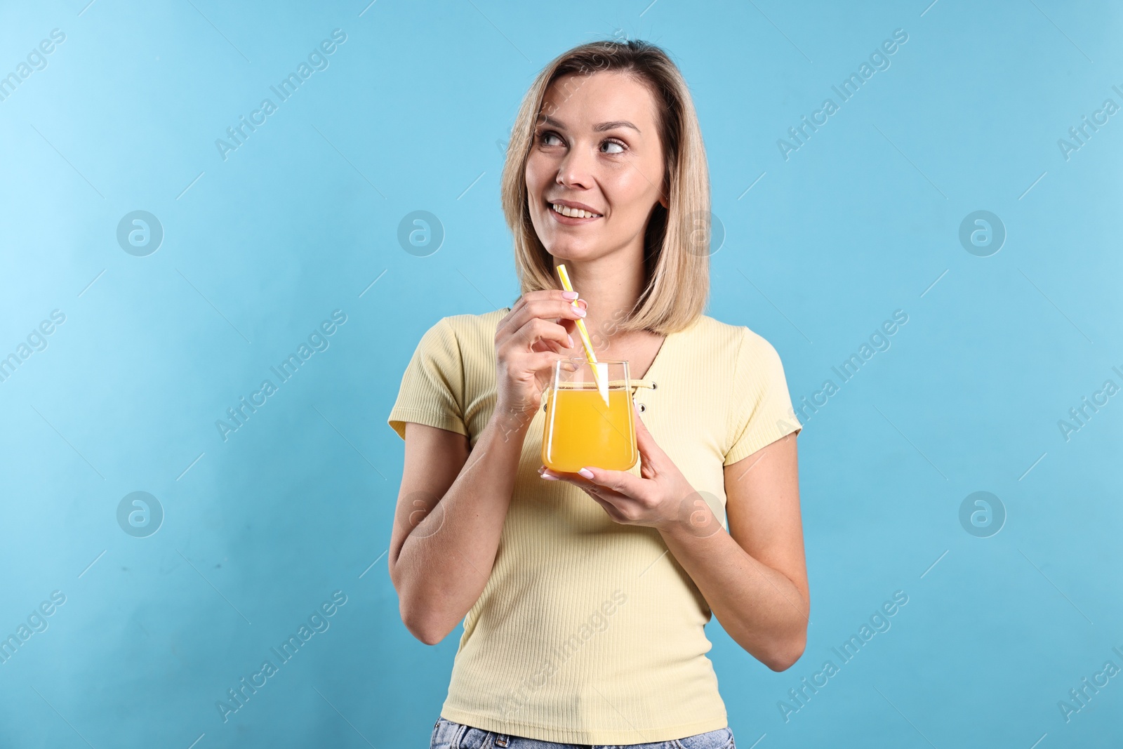 Photo of Woman with glass of orange juice on light blue background. Refreshing drink