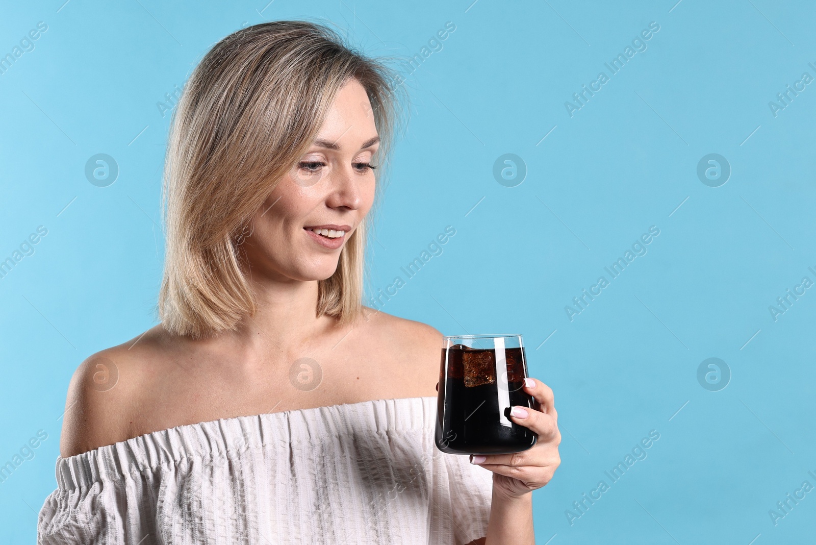 Photo of Woman with glass of refreshing soda drink on light blue background