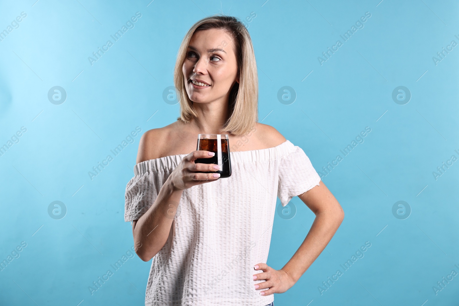 Photo of Woman with glass of refreshing soda drink on light blue background