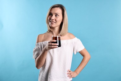 Photo of Woman with glass of refreshing soda drink on light blue background