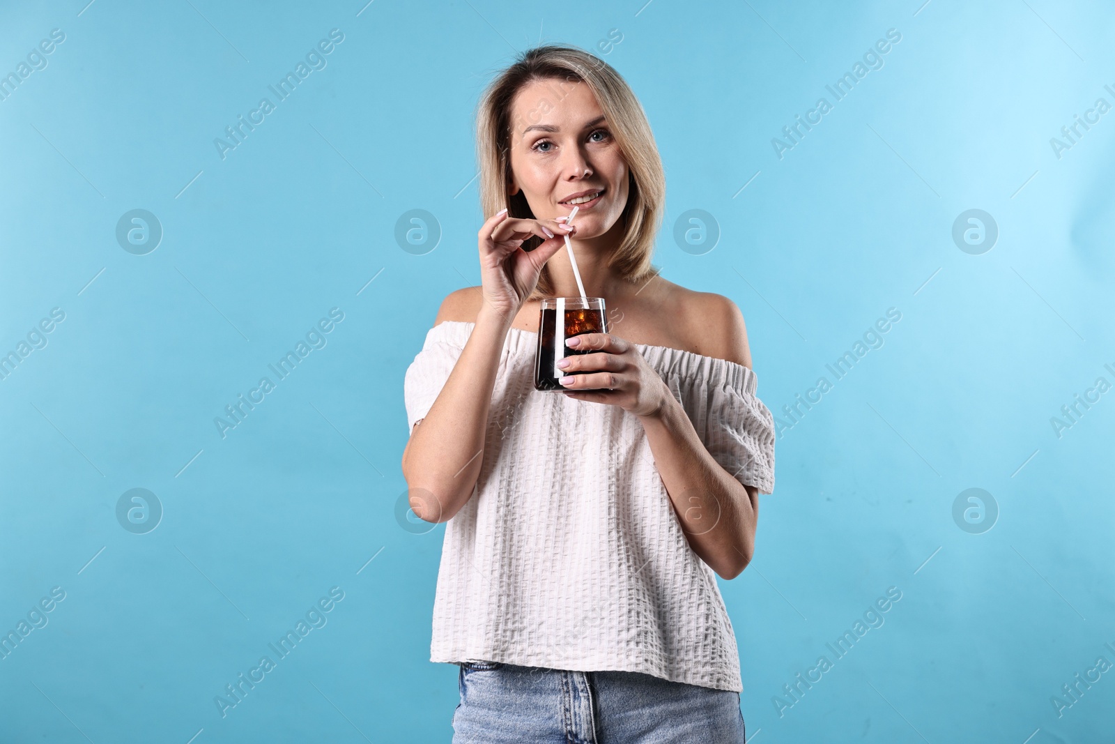 Photo of Woman with glass of refreshing soda drink on light blue background