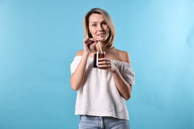 Photo of Woman with glass of refreshing soda drink on light blue background