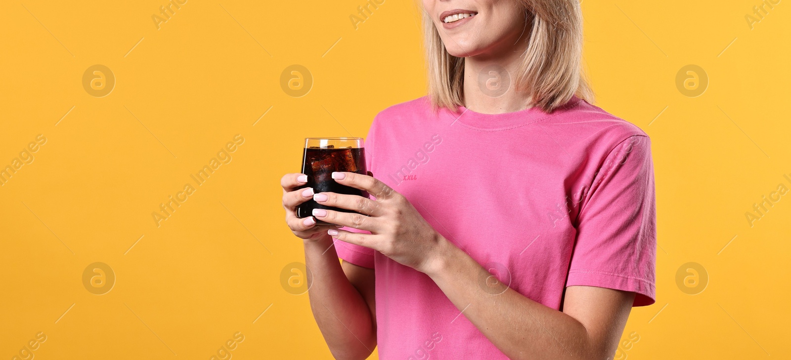 Photo of Woman with glass of refreshing soda drink on orange background, space for text