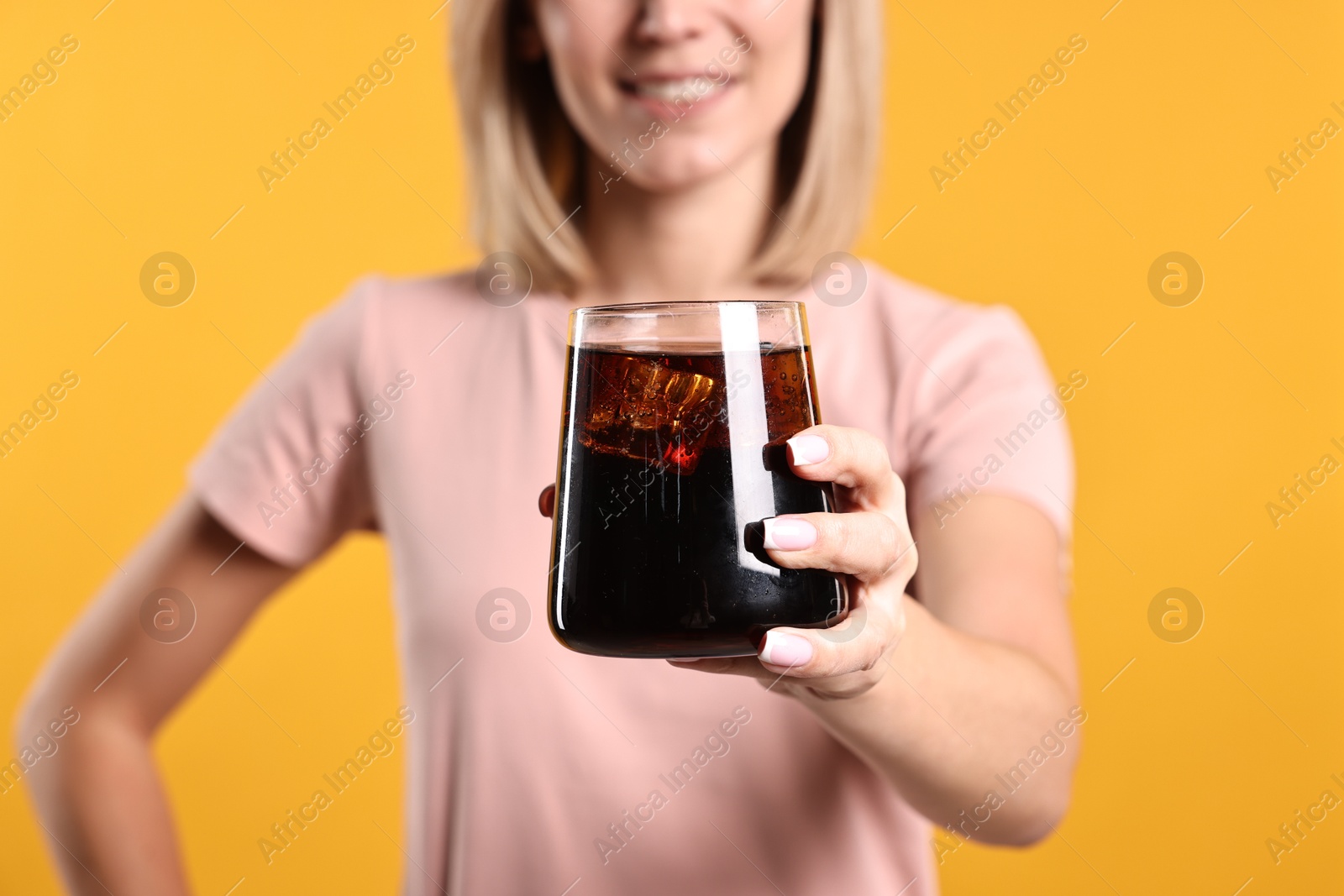 Photo of Woman with glass of refreshing soda drink on orange background, closeup