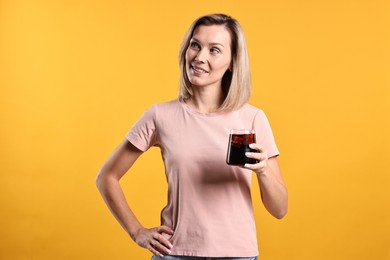 Photo of Woman with glass of refreshing soda drink on orange background.