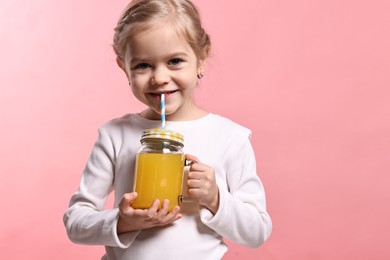 Photo of Girl with mason jar of orange juice on pink background. Refreshing drink