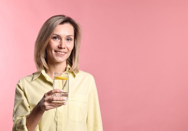 Photo of Woman with glass of lemonade on pink background. Refreshing drink