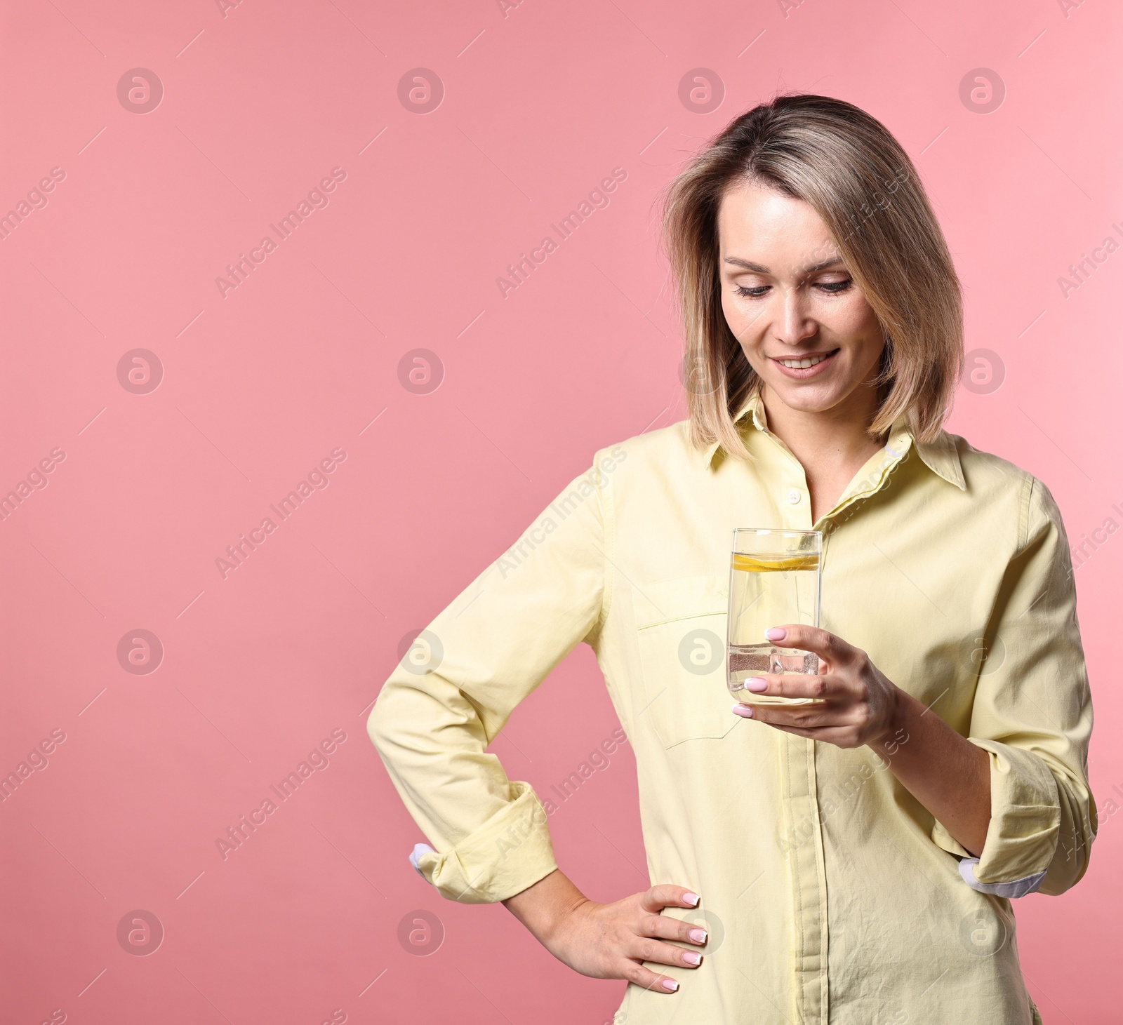 Photo of Woman with glass of lemonade on pink background. Refreshing drink