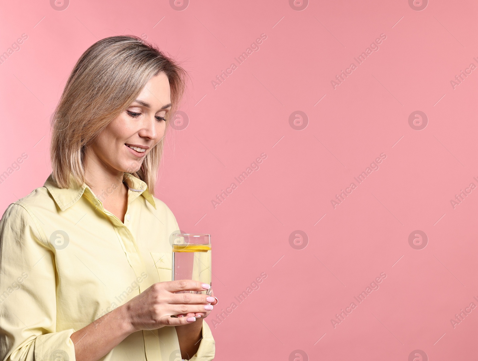 Photo of Woman with glass of lemonade on pink background. Refreshing drink