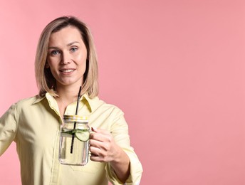 Photo of Woman with mason jar of lemonade on pink background. Refreshing drink