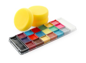 Photo of Bright face paint palette and sponges isolated on white