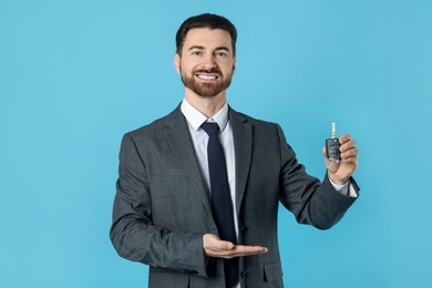 Photo of Cheerful salesman with car key on light blue background