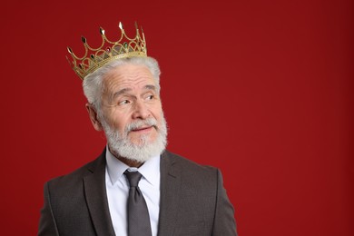 Photo of Senior man wearing luxury crown on red background, space for text