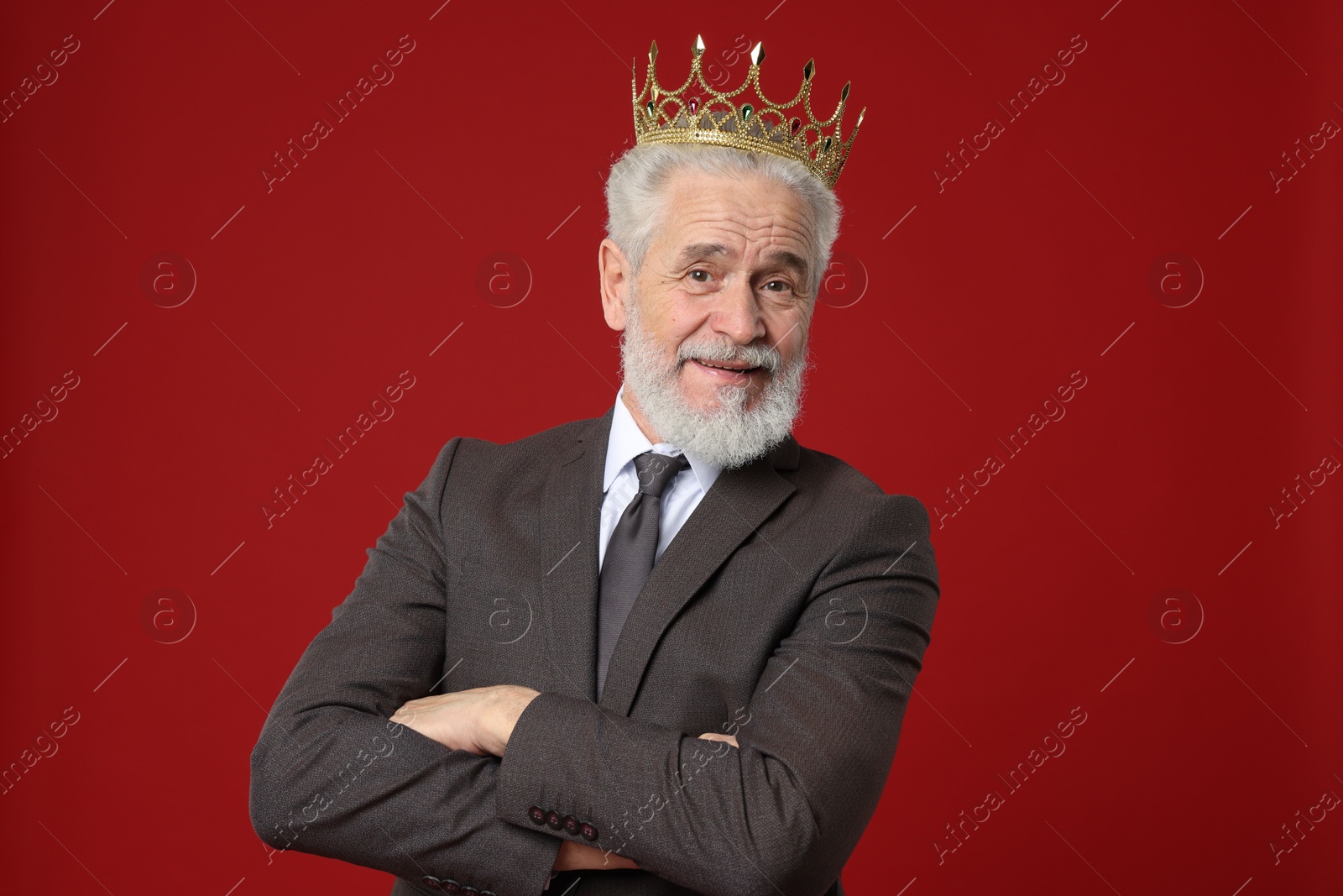 Photo of Senior man wearing luxury crown on red background