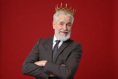 Photo of Senior man wearing luxury crown on red background