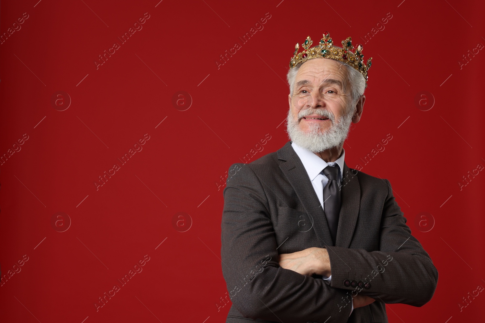 Photo of Senior man wearing luxury crown on red background, space for text