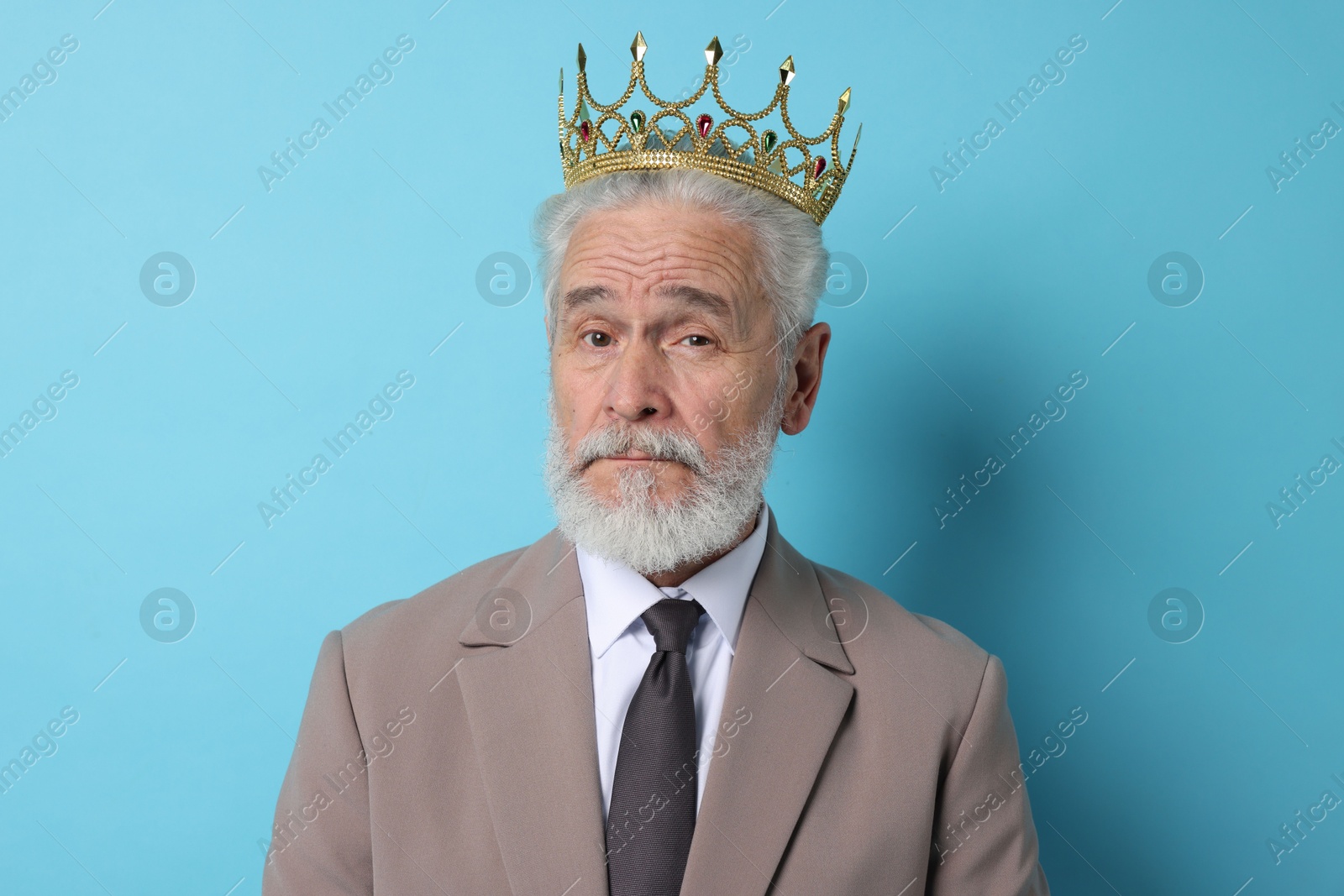 Photo of Senior man wearing luxury crown on light blue background