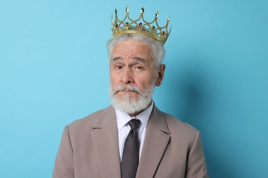 Photo of Senior man wearing luxury crown on light blue background