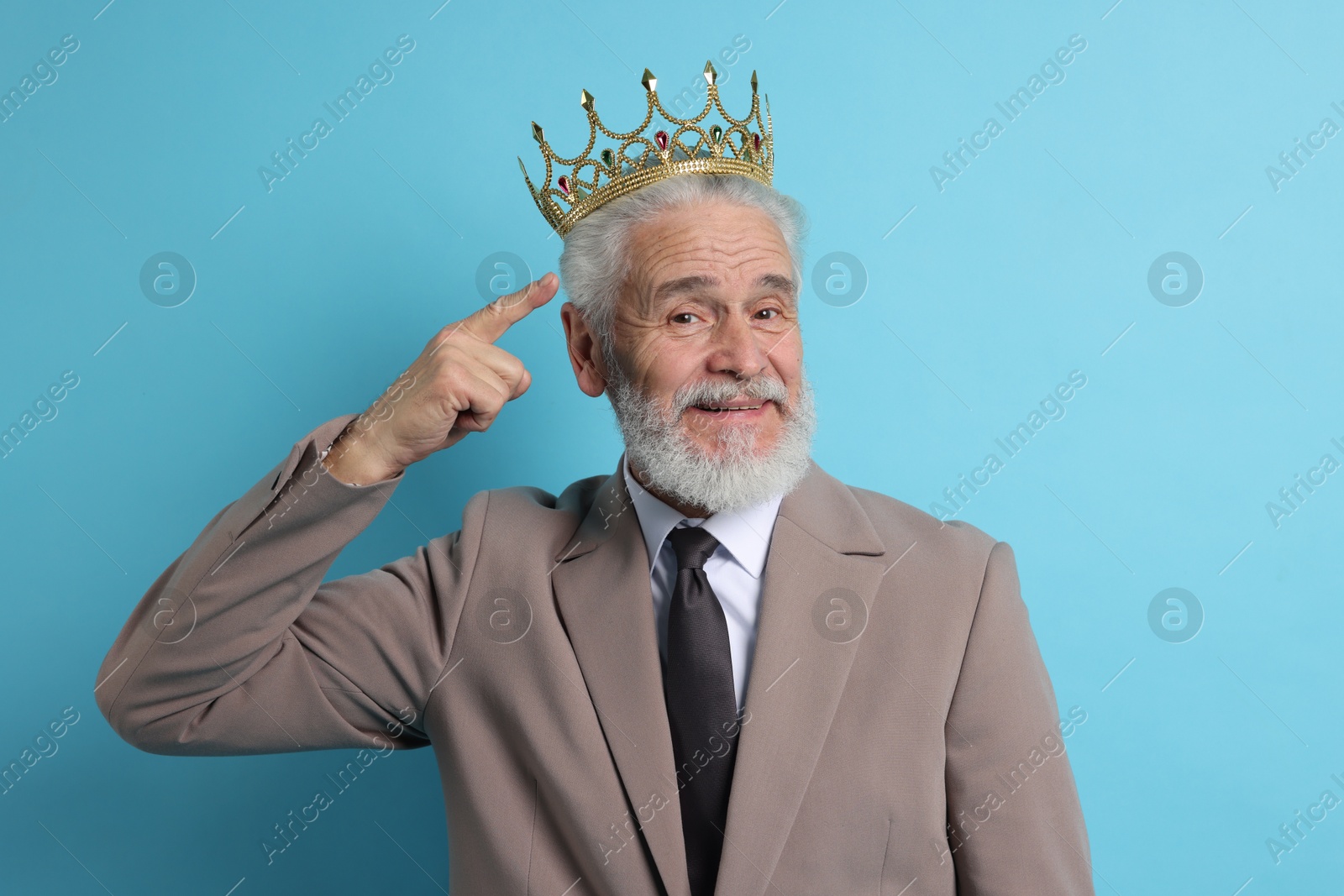 Photo of Senior man pointing at luxury crown on light blue background